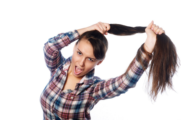 Amusing cheerful  girl  holding her long hair in ponytail over white background - Fotografie, Obrázek