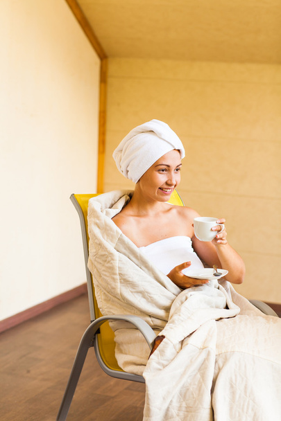 Молода жінка з білою чашкою кави або чаю після ванни в рушнику
 - Фото, зображення