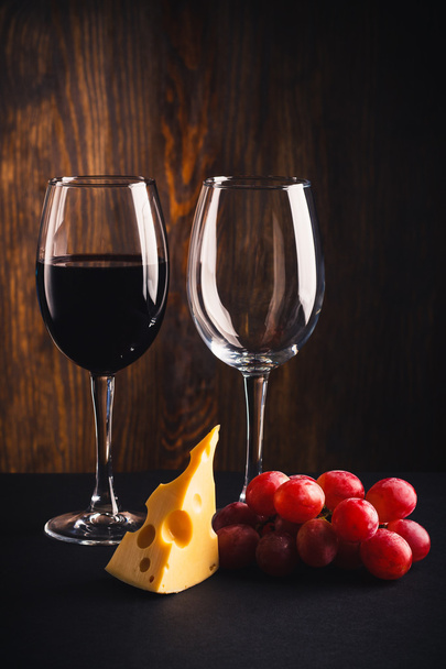 Two glasses, a pice of cheese and bunch of grapes - Photo, Image