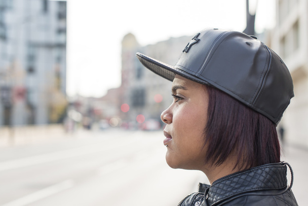Profile portrait of young woman with baseball cap in the street. - Photo, Image