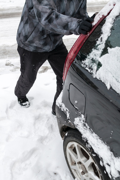 Man pushing car stuck in snow - Fotó, kép