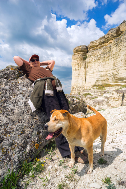 γυναίκα και το σκυλί κάθεται στην πέτρα κοντά υψώματα  - Φωτογραφία, εικόνα