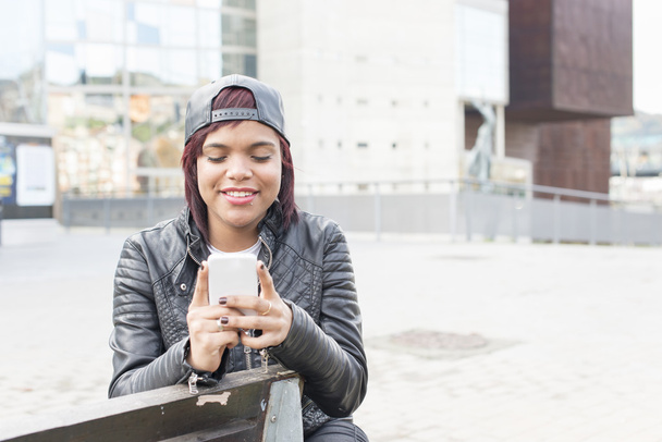 Usmívající se žena hledá zprávy na smartphonu v pojetí ulice, městského životního stylu. - Fotografie, Obrázek