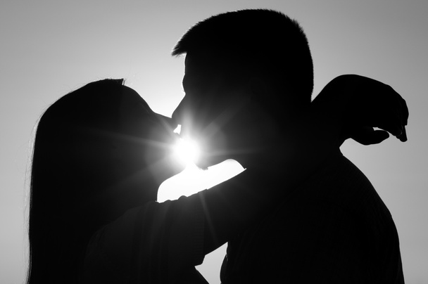 σιλουέτες των νεαρό ζευγάρι φιλιά στην ηλιόλουστη καλοκαιρινή μέρα - Φωτογραφία, εικόνα