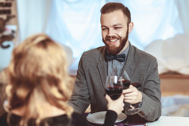 Beautiful young couple with glasses of red wine in luxury restaurant - Foto, Imagen
