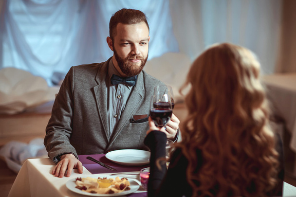 Beautiful young couple with glasses of red wine in luxury restaurant - Foto, Imagen