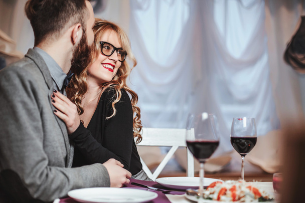 Beautiful young couple with glasses of red wine in luxury restaurant - Fotoğraf, Görsel