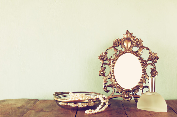 Antique blank victorian style frame, perfume bottle and white pearls on wooden table. retro filtered and toned. template, ready to put photography - Fotografie, Obrázek