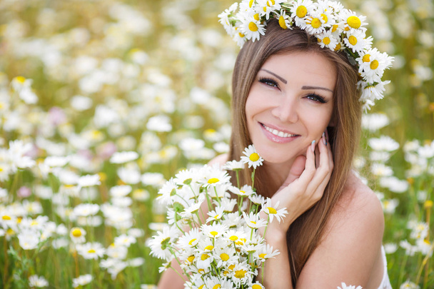 Beautiful young woman in a field of blooming daisies - Фото, изображение
