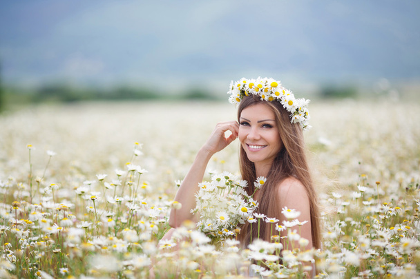 Beautiful young woman in a field of blooming daisies - Foto, afbeelding