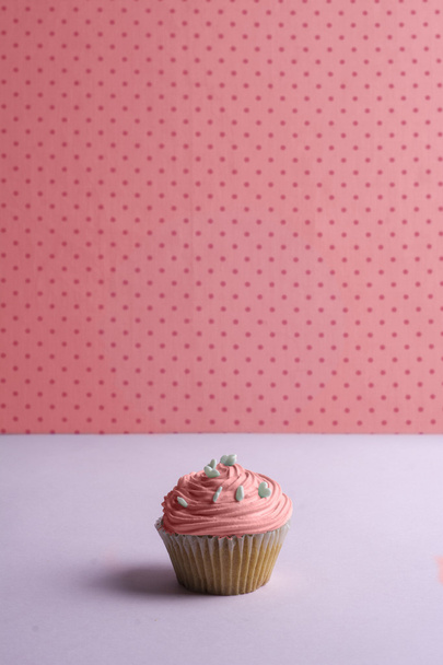Ροζ cupcake με κρέμα σαντιγί, και διάστικτη καρδιά ψεκάζει πάνω  - Φωτογραφία, εικόνα
