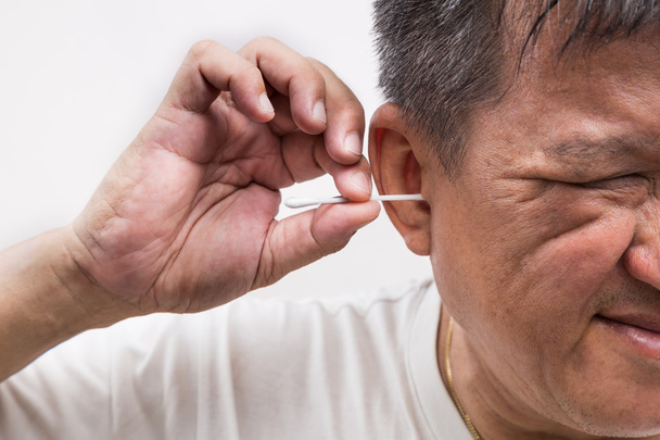 Мужчина чистит ухо ватными бутонами палкой с щекотливым выражением
 - Фото, изображение