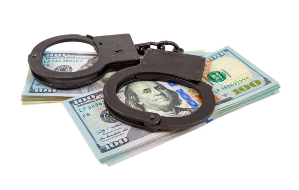 Steel handcuffs lying on a stack of dollar bills on the white background - Photo, Image