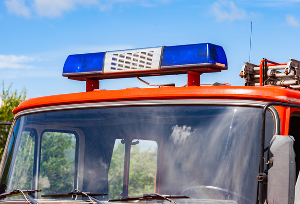 Κοντινό πλάνο του αναβοσβήνει μπλε φωτός σειρήνα στη στέγη του κόκκινο firetruck - Φωτογραφία, εικόνα