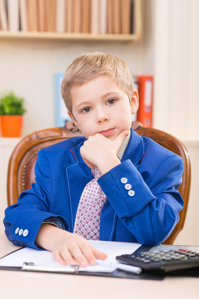 Little thoughtful boy sitting at the desk. - Fotó, kép