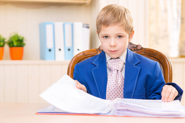Boy at the desk looking through a folder. - Fotó, kép