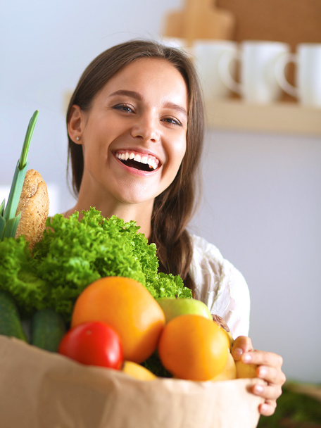Fiatal nő gazdaság élelmiszerbolt bevásárló táska zöldségekkel - Fotó, kép