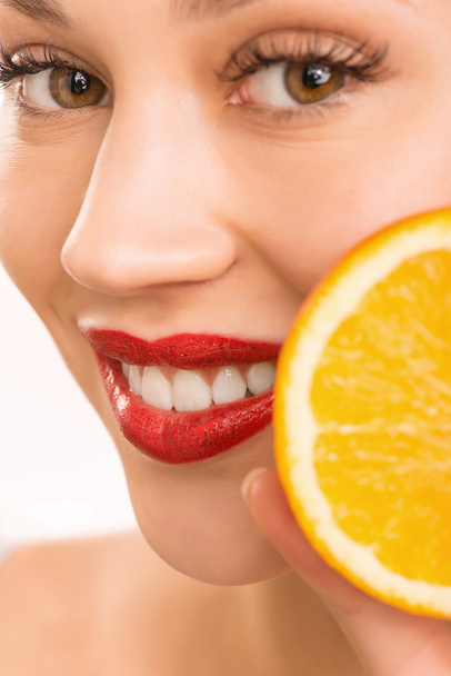 Smiling girl upholding an orange. - Zdjęcie, obraz