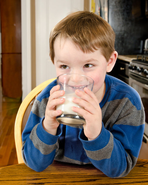 Young boy drinking milk at dinner table - Zdjęcie, obraz