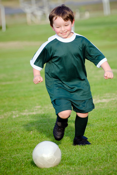 Young boy playing soccer in organized league game - Fotoğraf, Görsel