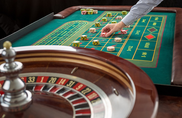 Roulette en stapels chips op een groene tafel gokken. - Foto, afbeelding