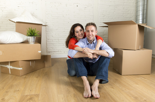 joven feliz pareja sentado en el suelo juntos celebrando la mudanza en nueva casa plana o apartamento
 - Foto, imagen