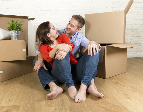 szczęśliwa para siedzi na podłodze z okazji poruszając się w nowe mieszkanie dom lub mieszkanie - Zdjęcie, obraz