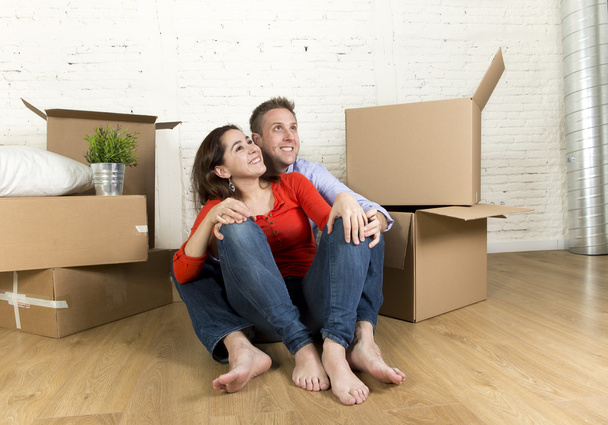 joven feliz pareja sentado en el suelo juntos celebrando la mudanza en nueva casa plana o apartamento
 - Foto, Imagen