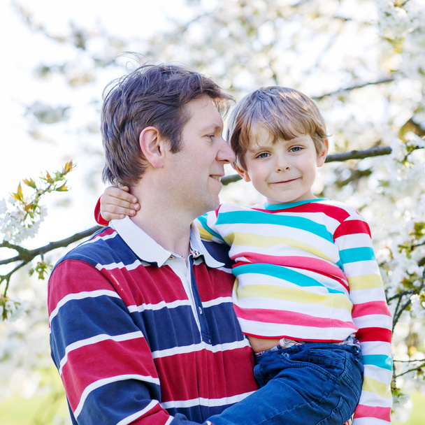 Mladý otec a dítě chlapec v rozkvetlé zahradě - Fotografie, Obrázek