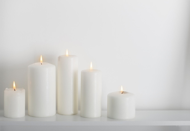 white candles burning on a white shelf  - Photo, image