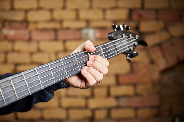 Head of a bass guitar and the fingers of the bassist - Photo, Image