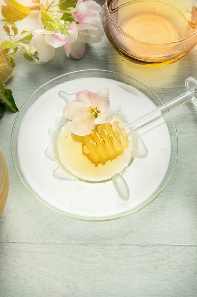 Glass plate with honey and dipper - Foto, afbeelding