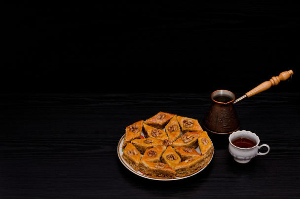 Цезе, кружка кофе и тарелка традиционной турецкой сладкой баклавы. Копирование пространства, черный фон
 - Фото, изображение