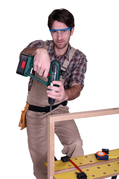 Carpenter screwing a frame together - Фото, изображение