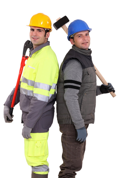 Tradesmen standing back to back and holding tools - Foto, afbeelding