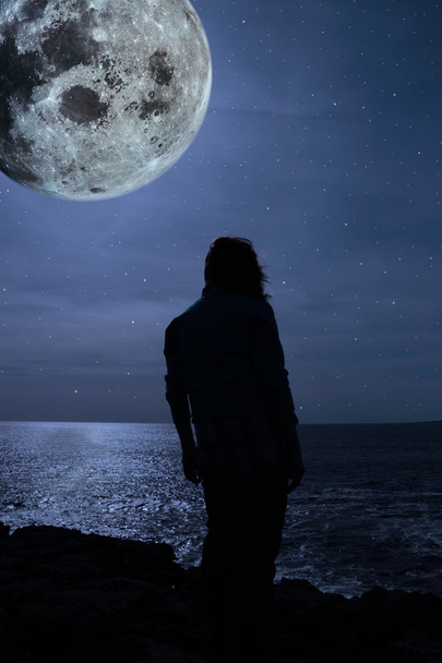 σιλουέτα του μια θλιβερή μοναχικός γυναίκα με ένα πλήρες φεγγάρι σε μια άκρη του βράχου - Φωτογραφία, εικόνα