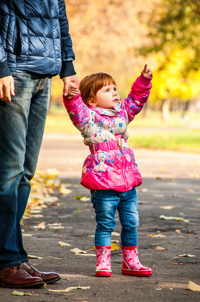 Little girl walks with my dad, pointing to something in the park - 写真・画像