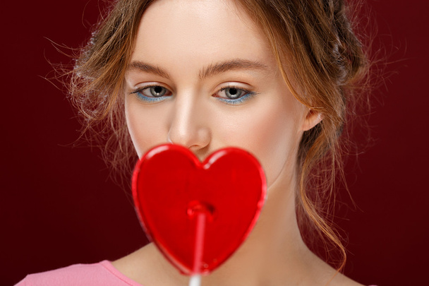 Valentine's Day. Young girl with red heart on red background. sad girl - Valokuva, kuva