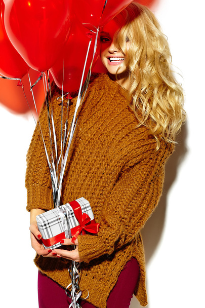 portrait of beautiful happy sweet smiling blonde woman girl holding in her hands Christmas gift box and heart balloons in casual brown hipster winter sweater clothes - Fotoğraf, Görsel