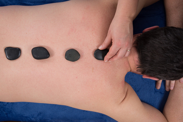 Man on a spa getting a hot stone massage. studio shot. - Photo, Image