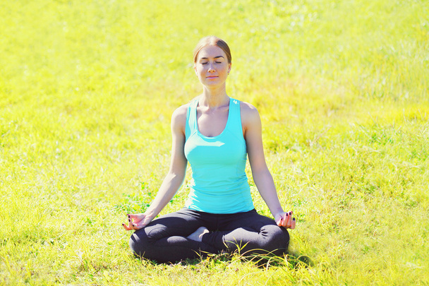 Yoga girl meditates sitting on grass pose lotus in sunny summer  - Zdjęcie, obraz