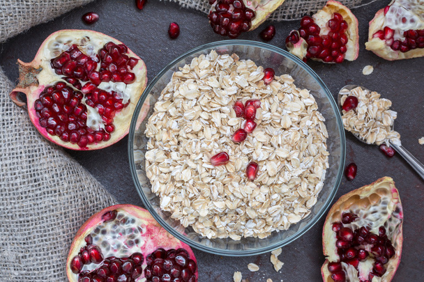 Raw oat flakes and fresh ripe garnet  - Фото, изображение