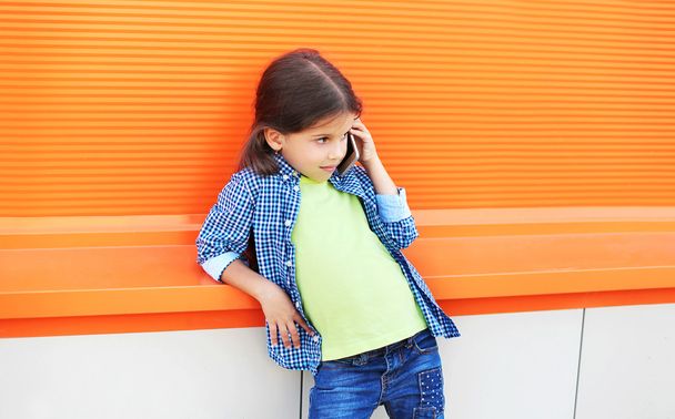 Beautiful little girl child talking on smartphone in city over c - Photo, Image