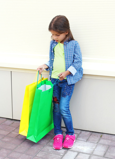 Beautiful little girl child with shopping colorful paper bags in - 写真・画像