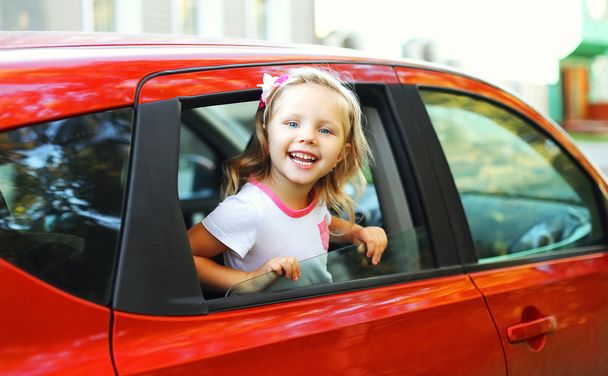 Portrait of happy smiling little child sitting in red car - Photo, Image