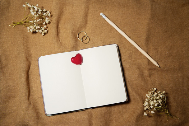 Blank notebook with heart and wedding rings on sackcloth backgro - Photo, Image