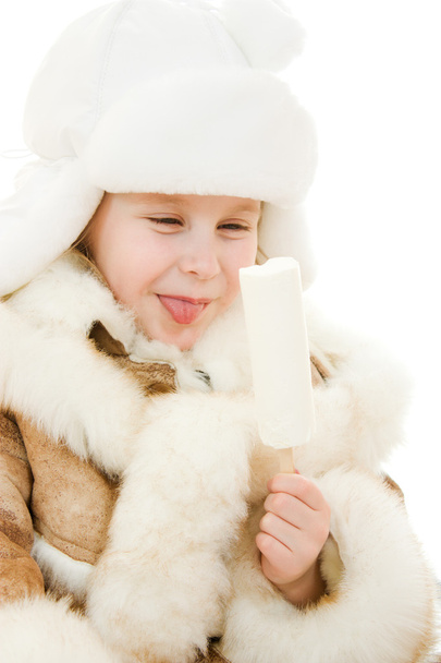The girl in warm clothes eating ice cream on white background. - 写真・画像