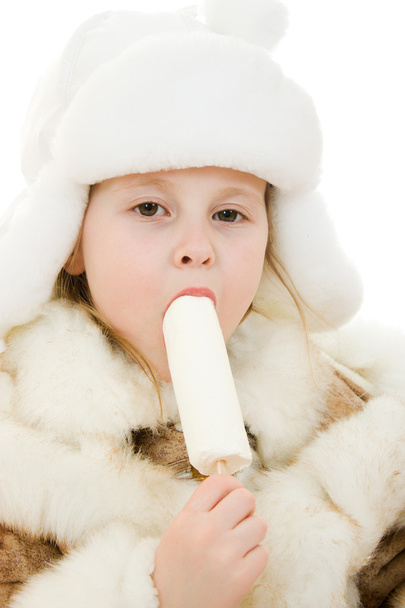 The girl in warm clothes eating ice cream on white background. - Foto, afbeelding