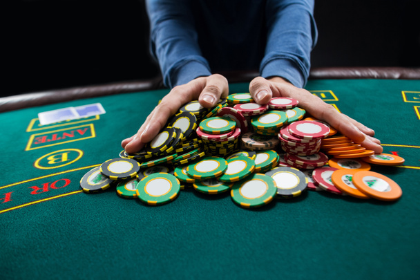 Игрок в покер собирается олл-ин толкая свои фишки вперед
 - Фото, изображение