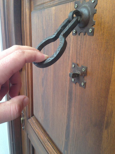 Man hand knocking with an old iron doorknocker - Photo, Image